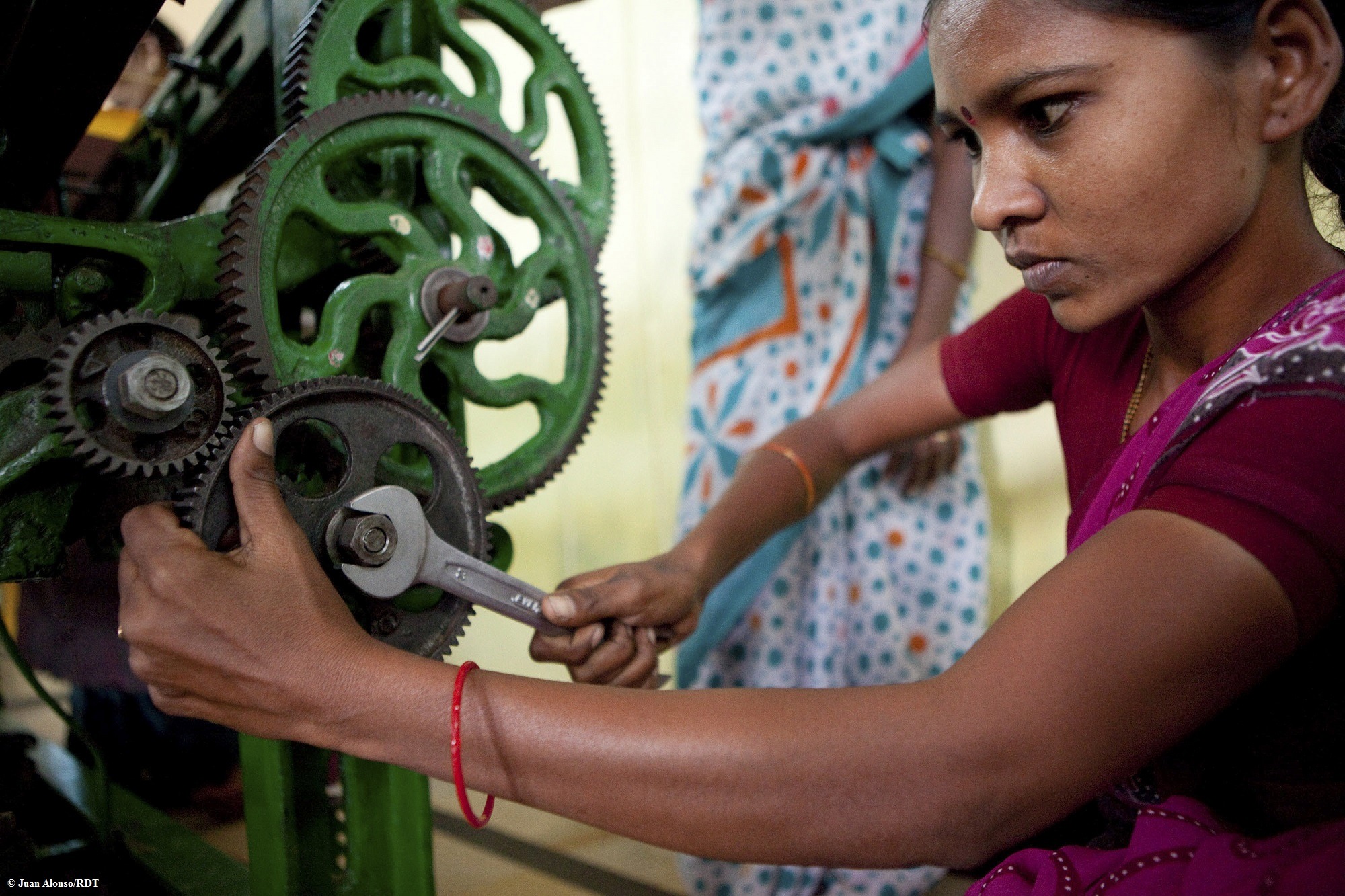 Frau in Indien mit lila Sari vor oranger Wand.