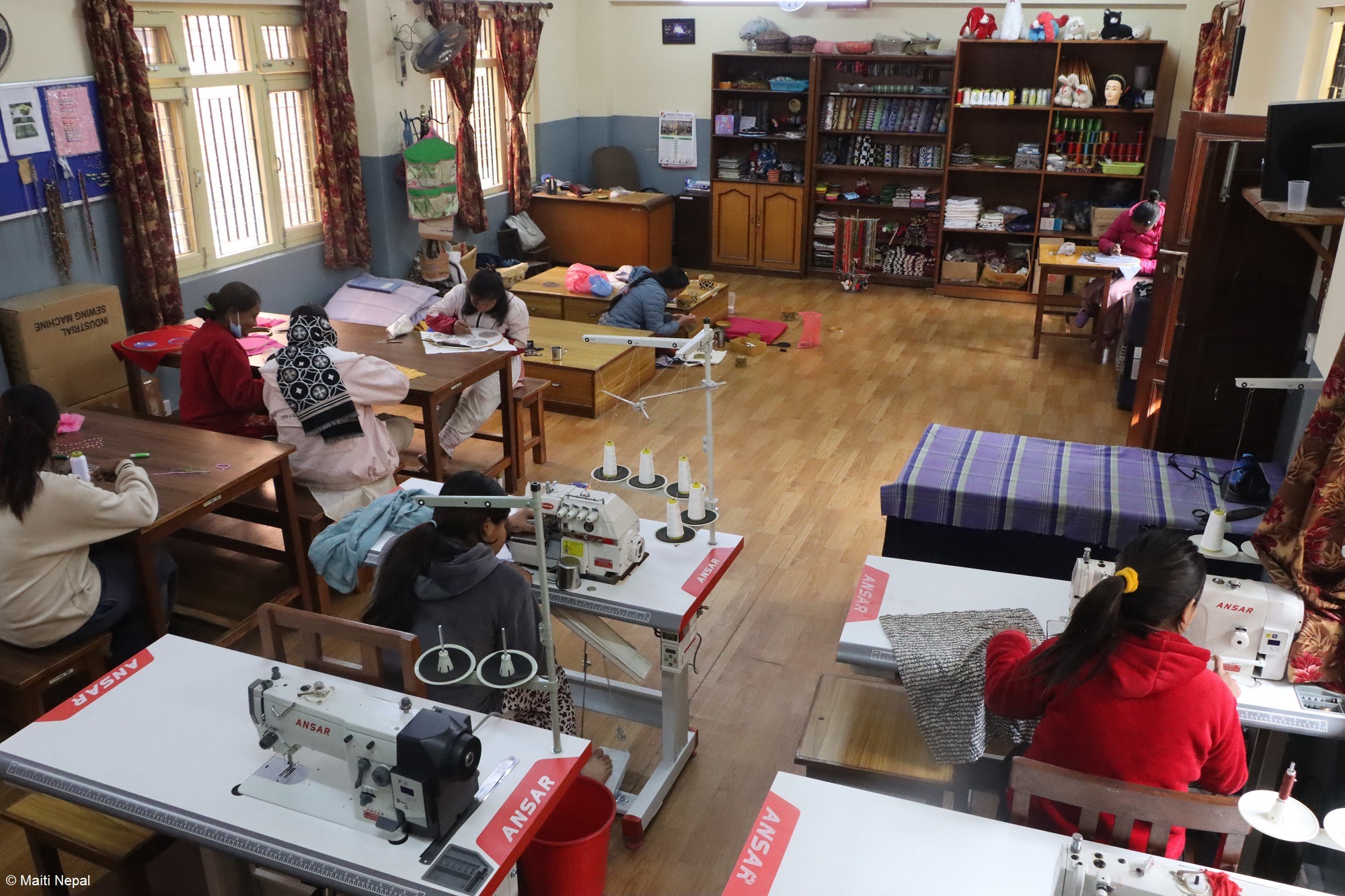 Frau in Indien mit lila Sari vor oranger Wand.