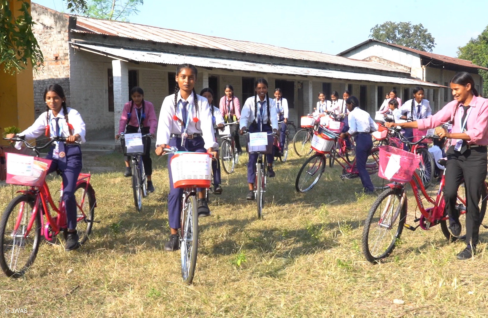 Zwei Männer und ein Kind stehen um einen neugepflanzten Baum herum und betrachten ihn. Landwirtschaft Indien: Aufforstung für den Klimaschutz in Indien.